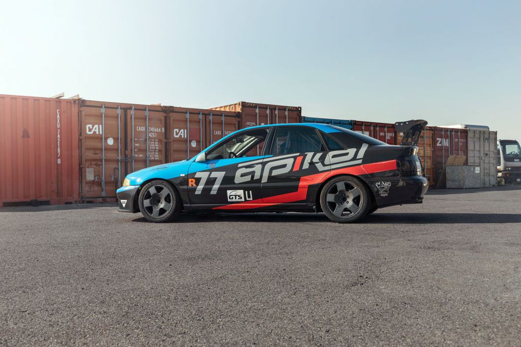 Apikol Performance Race Car Wrap in front of shipping containers